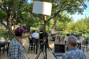 A crew films as a student sits at a table with a tablet on the Saint Mary's College campus.